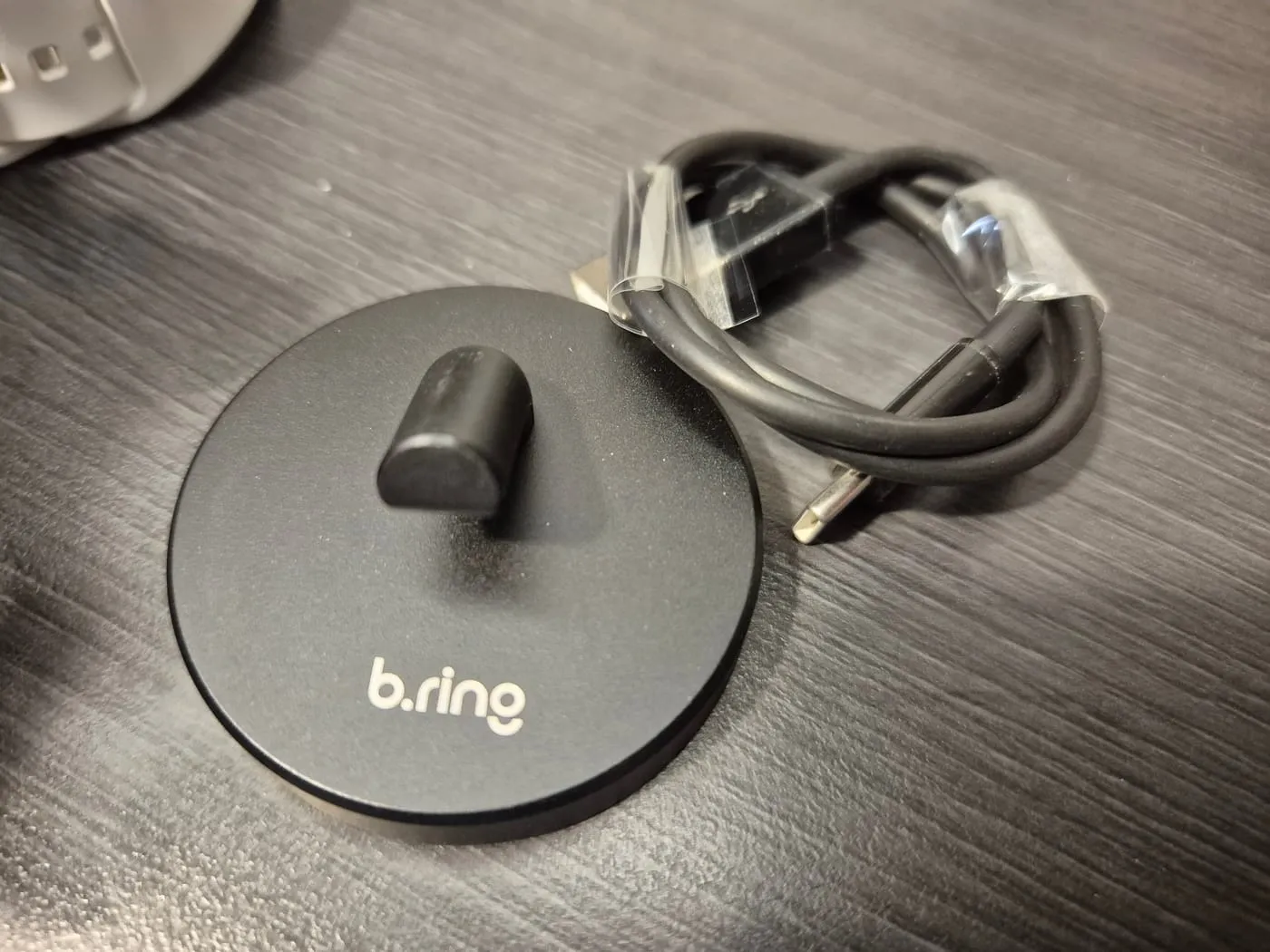원형 충전 독과 비닐 포장된 USB 케이블. 독 윗면에 b.ring 로고가 있다