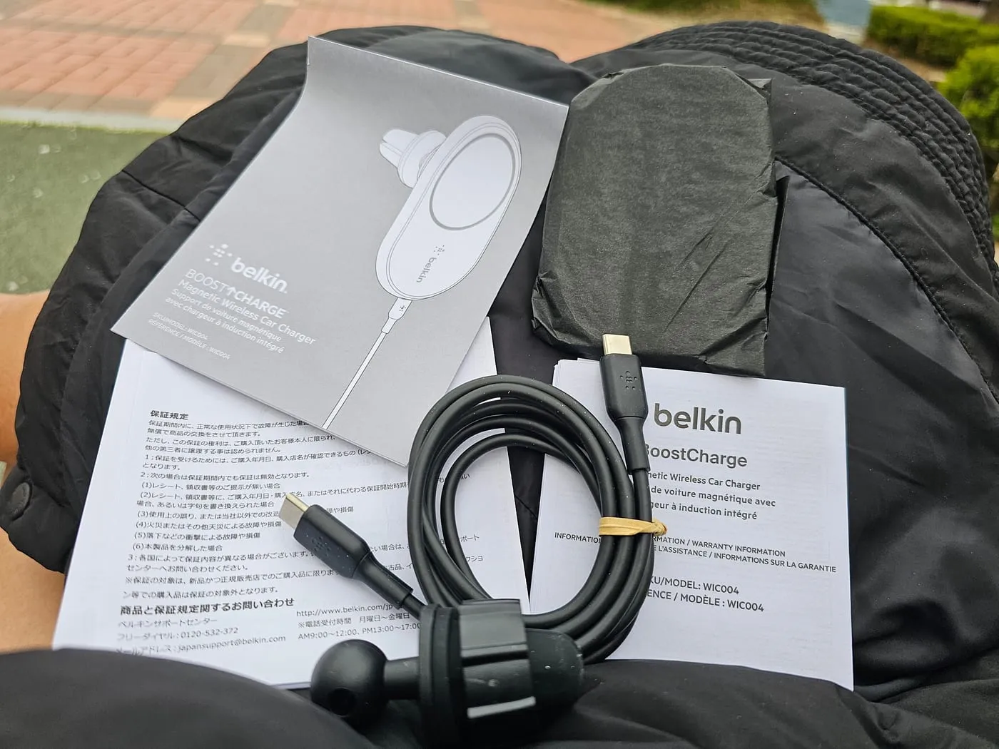 Box contents laid out: the charger with attached cable, the vent clip, and paperwork