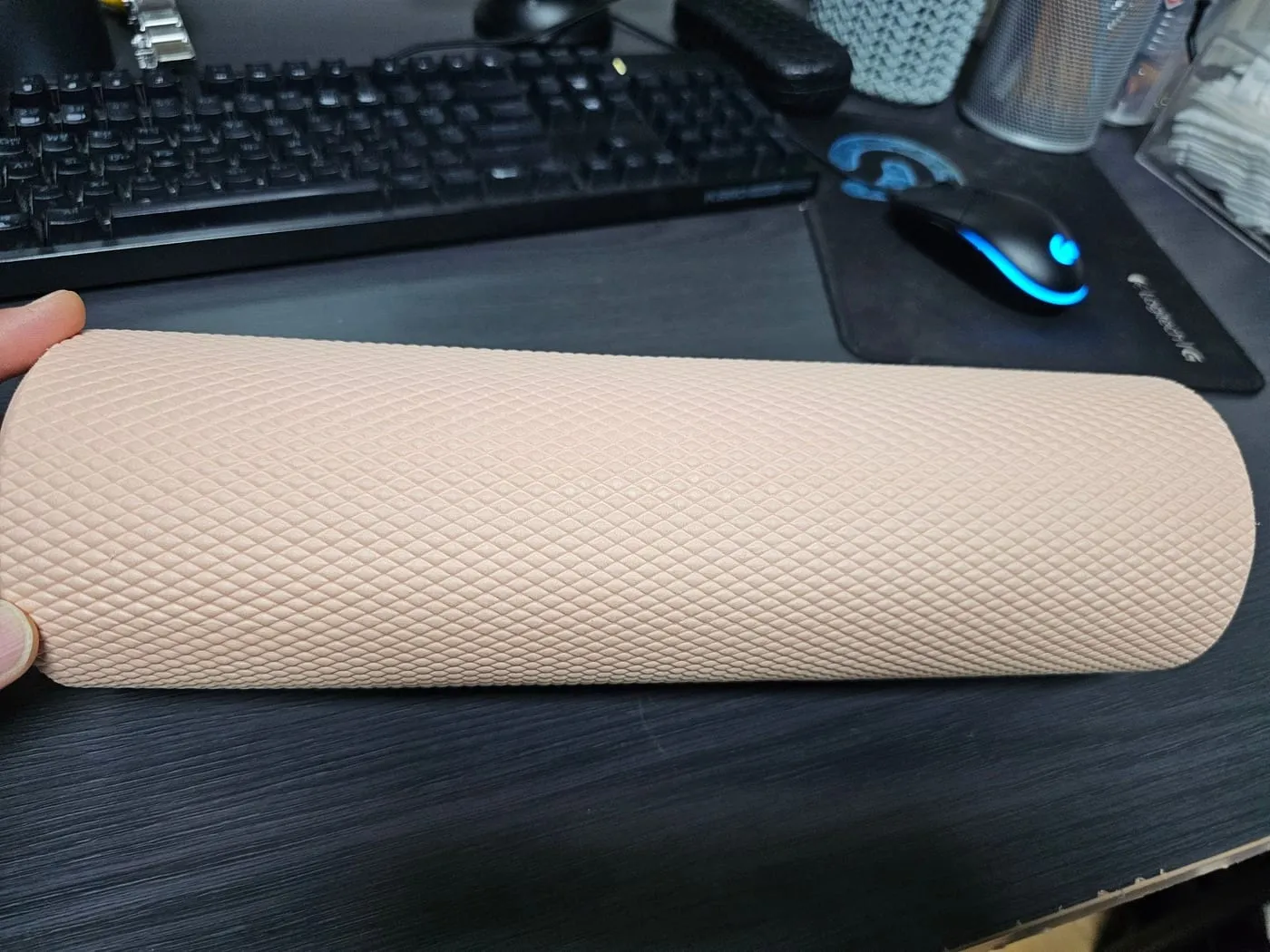 책상 위에 놓인 연한 살구색 폼롤러. 겉면 전체에 다이아몬드 격자 돌기가 있다