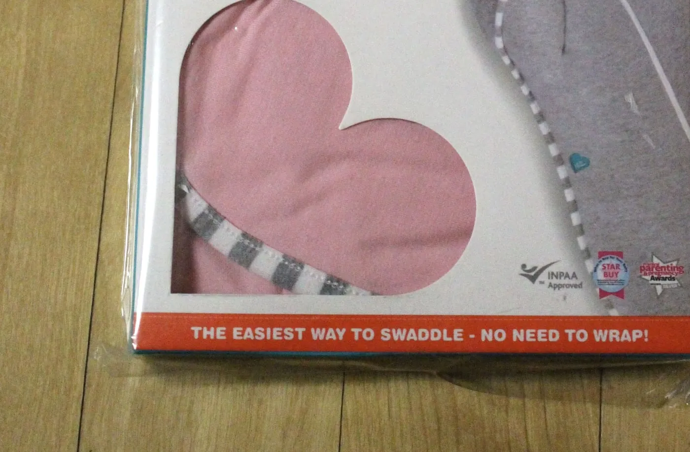 포장 아래쪽. 하트 모양 창, INPAA Approved 마크, THE EASIEST WAY TO SWADDLE - NO NEED TO WRAP! 문구