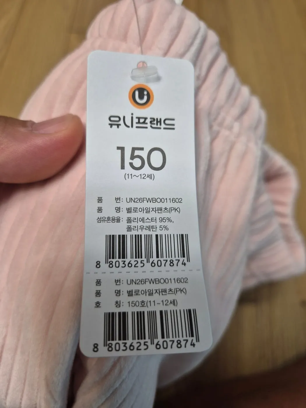 유니프랜드 택 확대. 150(11~12세), 품번 UN26FWBO011602, 품명 벨로아일자팬츠(PK), 섬유혼용률 폴리에스터 95% 폴리우레탄 5%, 바코드
