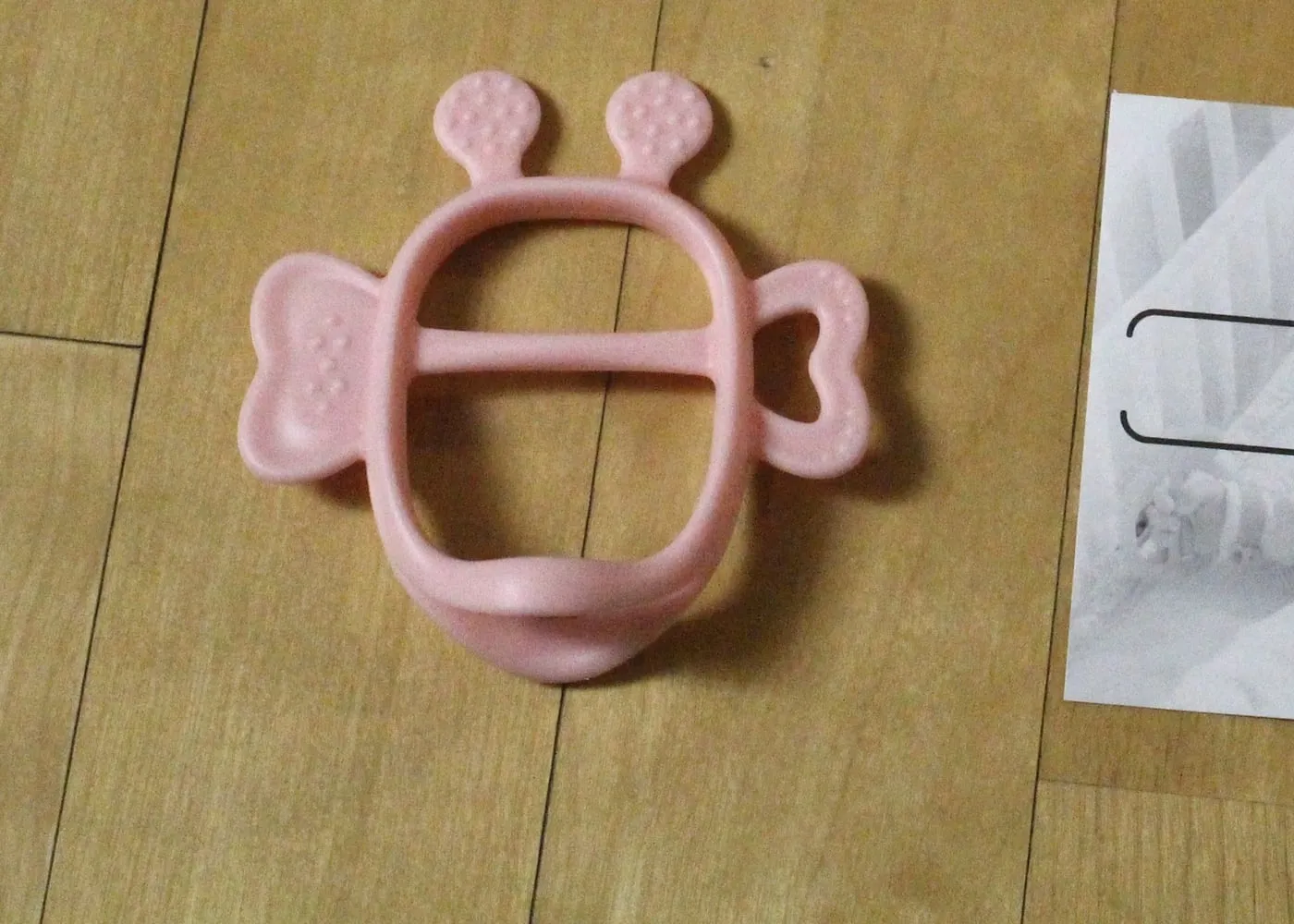 분홍색 꿀벌 모양 치발기. 큰 링 가운데 가로대, 위쪽 더듬이 두 개, 양옆 날개에 작은 돌기